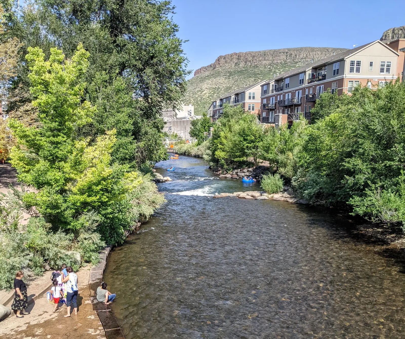 Clear Creek running through downtown Golden with tubers in the water and South Table Mountain beyond