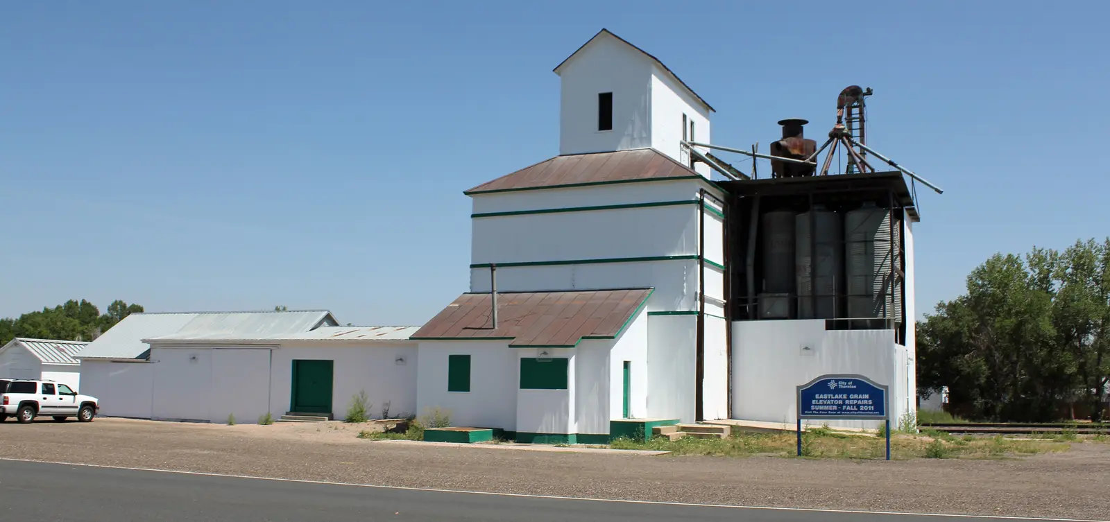 The historic white Eastlake Farmers Co-Operative grain elevator beside the rail line in Thornton, Colorado