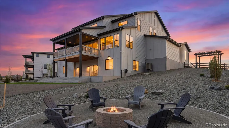Rear elevation at dusk with covered deck, lower patio and fire pit overlooking the canyon