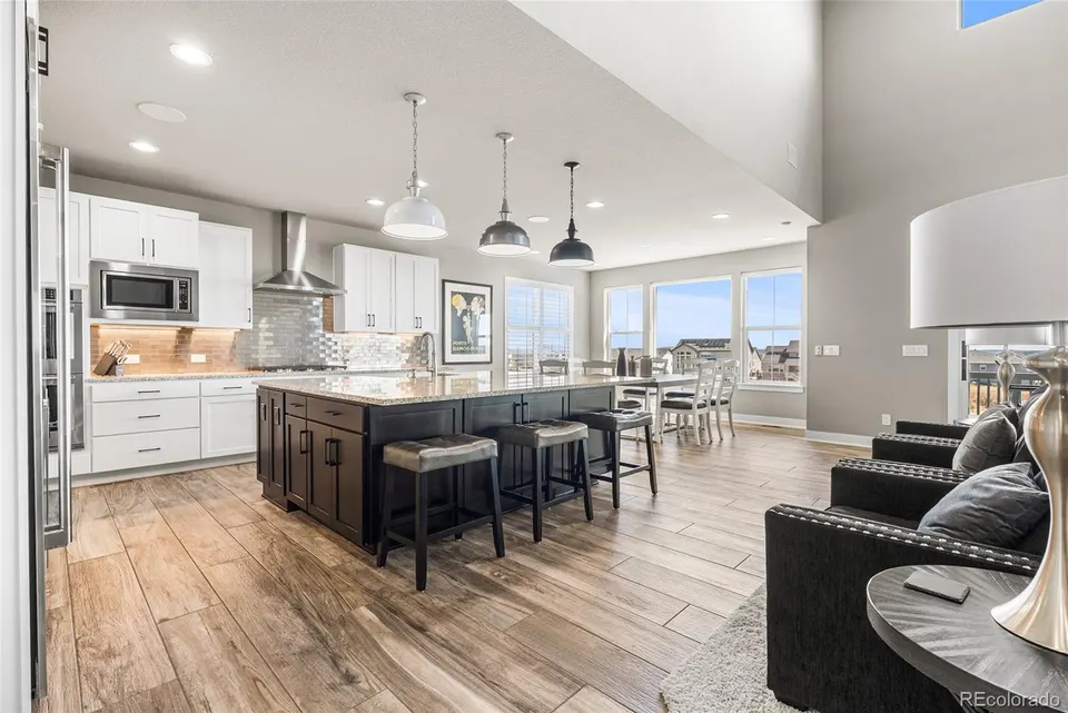 Open-concept kitchen with white cabinetry, dark island and pendant lighting