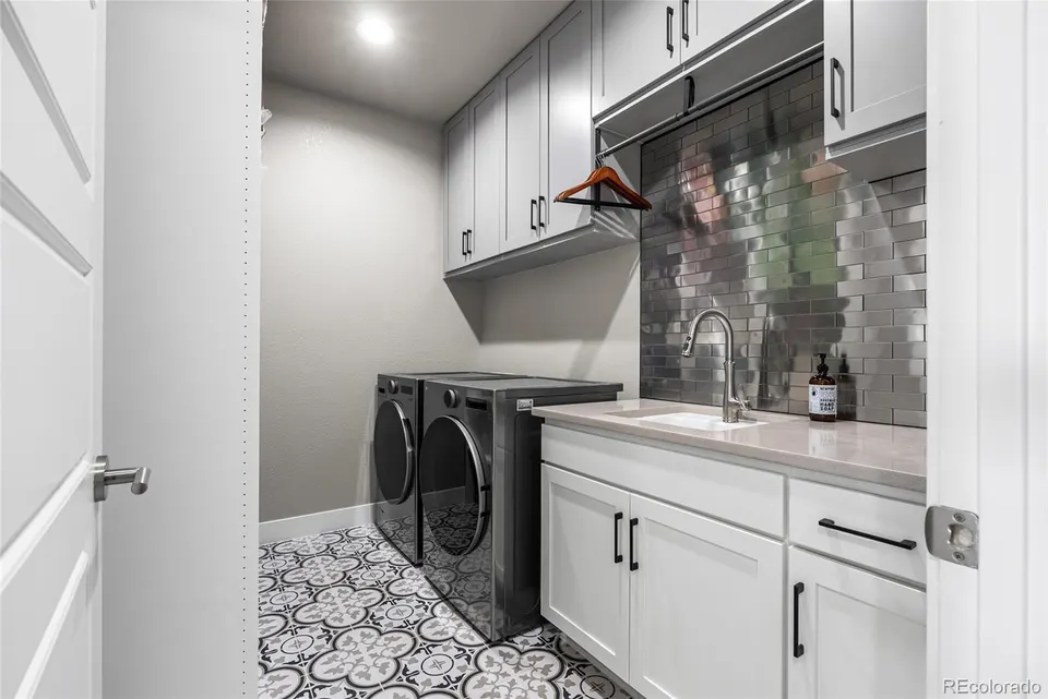 Laundry room with patterned tile floor and cabinetry
