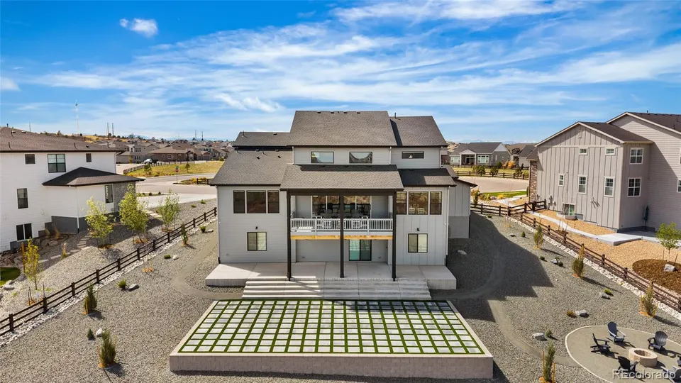 Rear aerial view of the home with lower-level patio and lawn