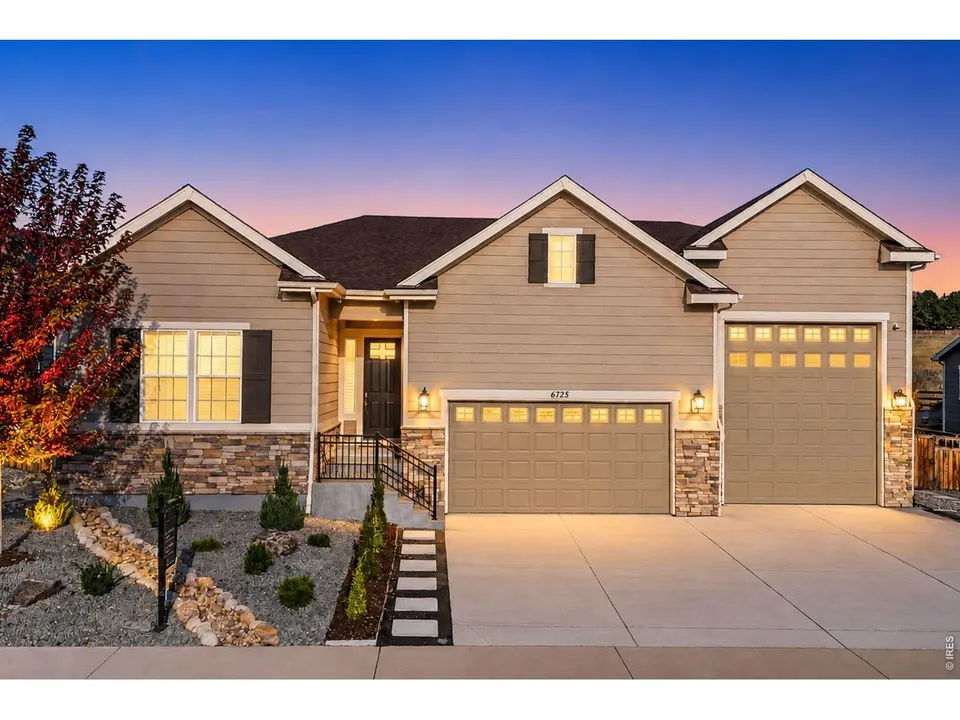 Twilight view of the stone-and-stucco ranch exterior at 6725 Mentha Drive with landscaped front yard