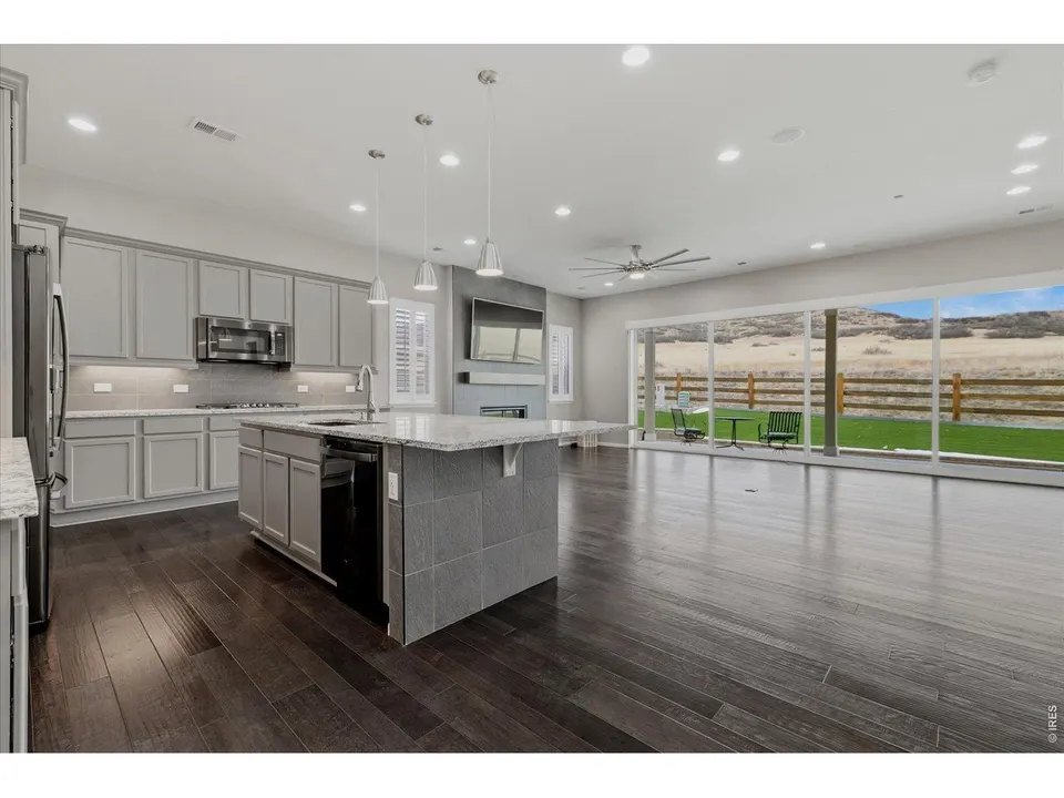 Open-concept kitchen and great room with dark hardwood floors and wall of glass to the patio